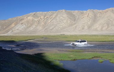 Off-road cars are fording a river along the Bartang Valley in the Gorno-Badakhshan in Tajikistan. The Badakhshan is an autonomous region in eastern Tajikistan, in the Pamir Mountains clipart