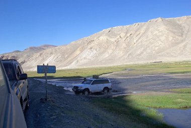 Off-road araçları Tacikistan 'daki Gorno-Badakhshan' daki Bartang Vadisi boyunca bir nehirde ilerliyor. Badakhshan, Tacikistan 'ın doğusunda, Pamir Dağları' nda özerk bir bölgedir.