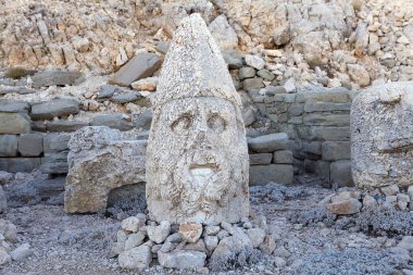 Türkiye 'nin güneyindeki Nemrut Dağı' nın doğu terasında tahtlar. Nemrut Dağı, MÖ 1. yüzyıldan kalma bir kraliyet mezarı olduğu düşünülen bir takım büyük heykellerin dikildiği zirve için dikkat çekicidir.. 