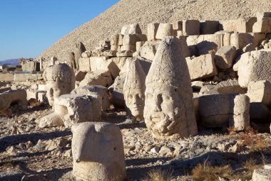 Türkiye 'nin güneyindeki Nemrut Dağı' nın doğu terasında tahtlar. Nemrut Dağı, MÖ 1. yüzyıldan kalma bir kraliyet mezarı olduğu düşünülen bir takım büyük heykellerin dikildiği zirve için dikkat çekicidir.. 