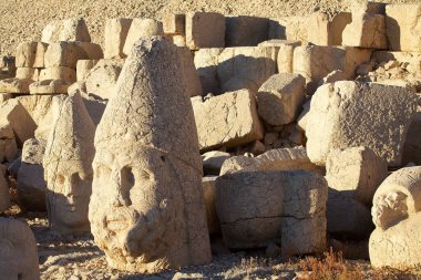 Türkiye 'nin güneyindeki Nemrut Dağı' nın doğu terasında tahtlar. Nemrut Dağı, MÖ 1. yüzyıldan kalma bir kraliyet mezarı olduğu düşünülen bir takım büyük heykellerin dikildiği zirve için dikkat çekicidir.. 