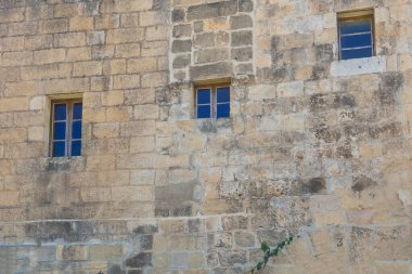 Taş bir binada üç mavi pencere.