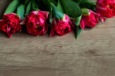 Bir buket kırmızı tırtıklı lale Ahşap bir masa