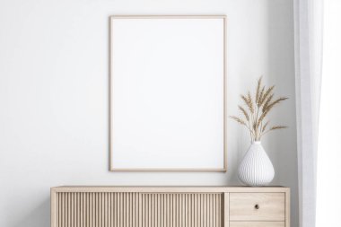 Ahşaptan yapılmış boş bir çerçeve ahşap bir dolabın duvarına asılı, pencerenin yanındaki beyaz perdelerle süslenmiş, minimalist bir çiçek vazosuyla süslenmiş..