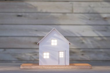 Masanın üstündeki tahta duvar arkaplanlı basit beyaz ev mimarisi modelinin ön görünümü 3d resimleme