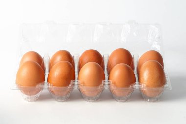 Satılık şeffaf plastik tepsi paketinde organik taze tavuk yumurtaları ve kesme yolu ile beyaz arka planda yumurtaların kırılmasını önler.