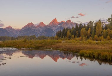 a beautiful sunrise landscape reflection in the Tetons in autumn