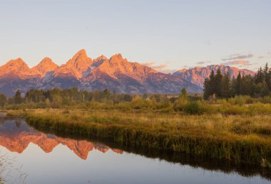 a beautiful sunrise landscape reflection in the Tetons in autumn
