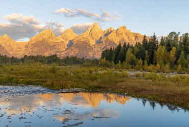 a beautiful sunrise landscape reflection in the Tetons in autumn