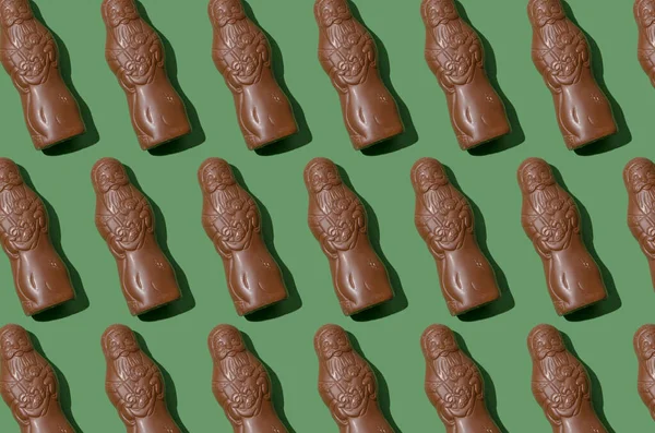緑の背景にチョコレートサンタクロースの図 甘いクリスマスキャンディ 休日の甘い食べ物を閉じます 治療だ 聖ニコラスチョコレートフィギュア — ストック写真