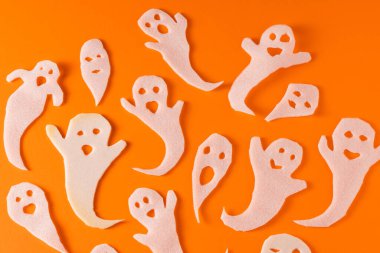 Beyaz hayaletler cadılar bayramı için el işi yapar. Turuncu arka planda kağıt hayaleti paketliyorum. Kendi ellerinle korkunç ve komik bir canavar oyuncağı. Korkunç Fısıltı çizgi filmi. El yapımıdır. Boo karakterlerini ayarla