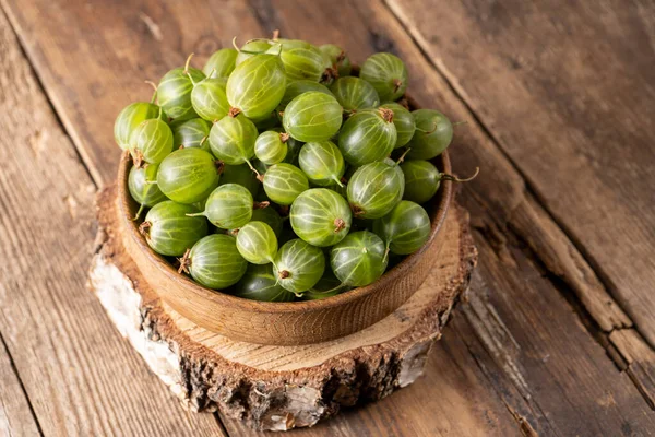 stock image Green gooseberries in a wooden bowl. Harvest berries on a wooden table. Gooseberry summer vitamin food.