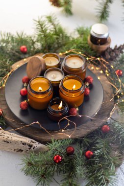 Soya mumları cam kavanozlarda yanar. Evdeki rahatlık. Kahverengi kavanozdaki mum. Koku ve ışık. Kokulu el yapımı mum. Aroma terapisi. Noel ağacı ve kış havası. Hoş bir dekor. Şenlikli çelenk dekorasyonu
