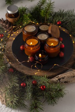 Soya mumları cam kavanozlarda yanar. Evdeki rahatlık. Kahverengi kavanozdaki mum. Koku ve ışık. Kokulu el yapımı mum. Aroma terapisi. Noel ağacı ve kış havası. Hoş bir dekor. Şenlikli çelenk dekorasyonu