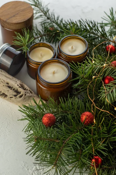 Soy candles burn in glass jars. Comfort at home. Candle in a brown jar. Scent and light. Scented handmade candle. Aroma therapy. Christmas tree and winter mood. Cozy decor. Festive garland decoration