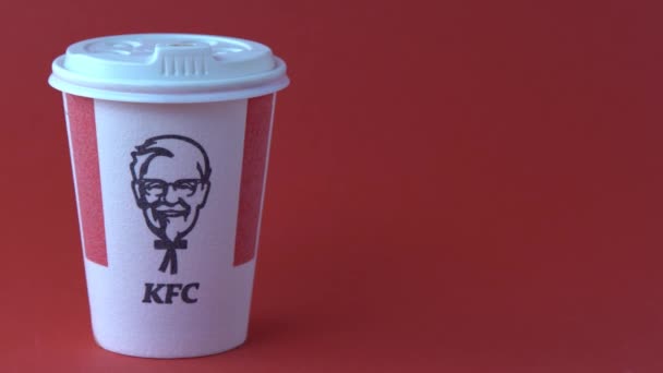 赤色の背景にコーヒー ココア 紅茶用Kfcの赤白ガラス ホットドリンクを移動します ケンタッキーフライドチキンのロゴ ファーストフードレストラン ハーランド サンダース ウクライナ キエフ — ストック動画