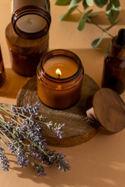Cam kavanozdaki soya mumları. Aromaterapi. Yanan mum ve lavanta. Kavanozlar için tahta kapak. Bej arka plan. Rahatlık ve rahatlama. El yapımı. Ev dekoru.