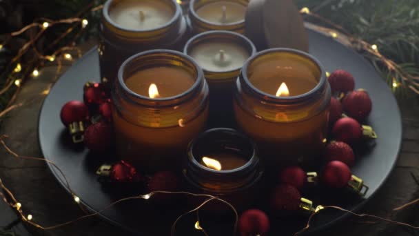 大豆蜡烛在玻璃瓶中燃烧 在家里很舒服把蜡烛放在棕色的罐子里 光芒四射有香味的手工蜡烛芳香疗法 圣诞树和冬天的心情 舒适的家居装饰 红球装饰 — 图库视频影像