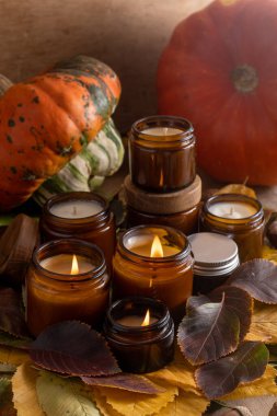 Soya mumları cam kavanozlarda yanar. Ağaç yaprakları, balkabağım. Evdeki rahatlık. Kahverengi kavanozdaki mum. Koku ve ışık. Kokulu el yapımı mum. Aroma terapisi. Sonbahar havası. Sonbaharda rahat ev dekorasyonu.