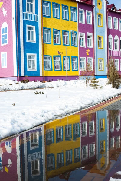 Colorful bright house. The building of the school and kindergarten for children. Architecture of Ukraine. Ukrainian village. Reflection in a puddle.