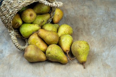 Ahşap bir arka planda sepetteki armutlar. Meyve hasadı. Sonbahar hala hayattır. Armut çeşitliliğinde Bera Konferansı. Vitamin yiyeceği..