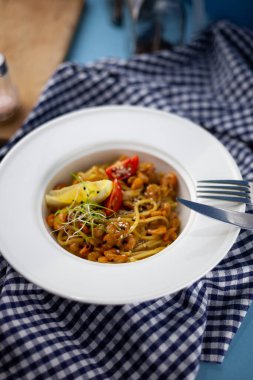 Karidesli spagetti, limon ve mikroyeşil. Öğle yemeği beyaz tabakta, yakın plan. Deniz ürünleri, domates ve salatalı makarna..