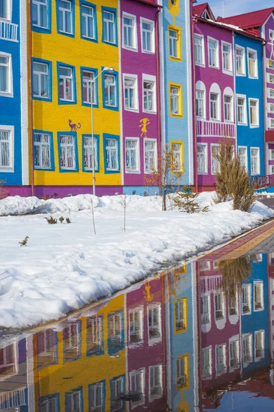 Colorful bright house. The building of the school and kindergarten for children. Architecture of Ukraine. Ukrainian village. Reflection in a puddle.