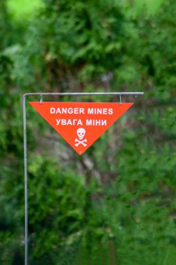 Danger mines. Sapper minefield warning sign on green background. Jolly Roger - white skull crossbones on a red sign of the danger of landmines. Military mine. War in Ukraine. Ukrainian translation