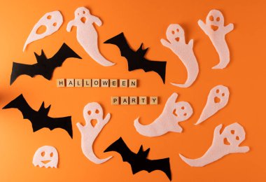 White ghosts and bat craft for Halloween party. Wrapping paper ghost on orange background top view. Cartoon creepy Whisper. DIY hand made. Set boo characters. Word wooden letter phrase.
