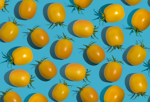Yellow cherry tomato pattern on a blue background. Bright vegetable. Vitamin food.