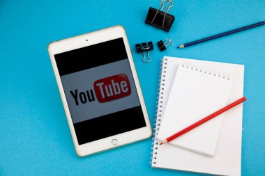 iPad for distance learning, work and entertainment. YouTube logo on iPhone tablet. Blogging and channel. Plan. Pen and notebook on the table. Planning. Kyiv, Ukraine - March 31, 2020