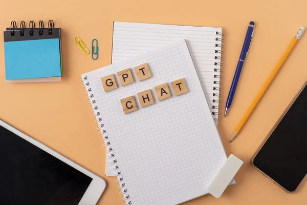 Work and study background with the help of a chatGPT bot. Words in wooden letters. Table top view with open notebook copy space. Chat GPT for working and creating