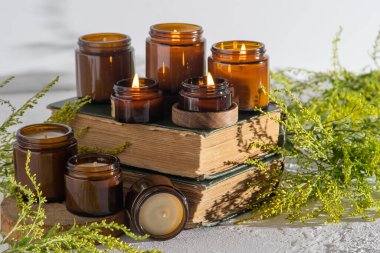 A set of different aroma candles in brown glass jars. Scented handmade candle. Soy candles are burning in a jar. Aromatherapy and relax in spa and home. Fire in brown jar. Yellow flowers