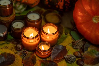 Soya mumları cam kavanozlarda yanar. Ağaç yaprakları, balkabağım. Evdeki rahatlık. Kahverengi kavanozdaki mum. Koku ve ışık. Kokulu el yapımı mum. Aroma terapisi. Sonbahar havası. Sonbaharda rahat ev dekorasyonu.