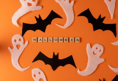 White ghosts and bat craft for Halloween party. Wrapping paper ghost on orange background top view. Cartoon creepy Whisper. DIY hand made. Set boo characters. Word wooden letter phrase.