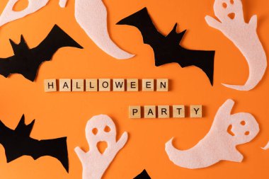 White ghosts and bat craft for Halloween party. Wrapping paper ghost on orange background top view. Cartoon creepy Whisper. DIY hand made. Set boo characters. Word wooden letter phrase.