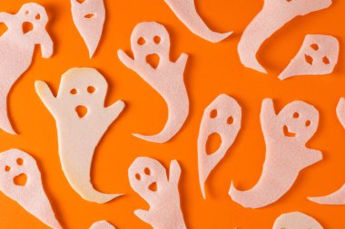 Beyaz hayaletler cadılar bayramı için el işi yapar. Turuncu arka planda kağıt hayaleti paketliyorum. Kendi ellerinle korkunç ve komik bir canavar oyuncağı. Korkunç Fısıltı çizgi filmi. El yapımıdır. Boo karakterlerini ayarla