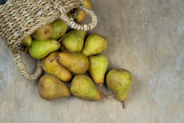 Ahşap bir arka planda sepetteki armutlar. Meyve hasadı. Sonbahar hala hayattır. Armut çeşitliliğinde Bera Konferansı. Vitamin yiyeceği..