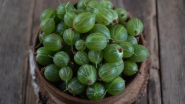 Green gooseberries in a wooden bowl. Harvest berries on a wooden table. Gooseberry summer vitamin food.