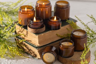 A set of different aroma candles in brown glass jars. Scented handmade candle. Soy candles are burning in a jar. Aromatherapy and relax in spa and home. Fire in brown jar. Yellow flowers