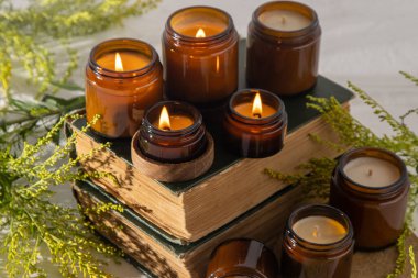 A set of different aroma candles in brown glass jars. Scented handmade candle. Soy candles are burning in a jar. Aromatherapy and relax in spa and home. Fire in brown jar. Yellow flowers