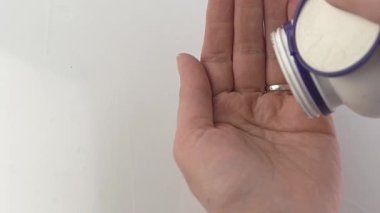 Eline bir doz tablet dök. Tablet tedavisi. Vitaminler, beslenme takviyesi, ağrı kesiciler ve antipiretikler. Eczacılık. Eczane. Beyaz haplar. Sağlık tedavisi