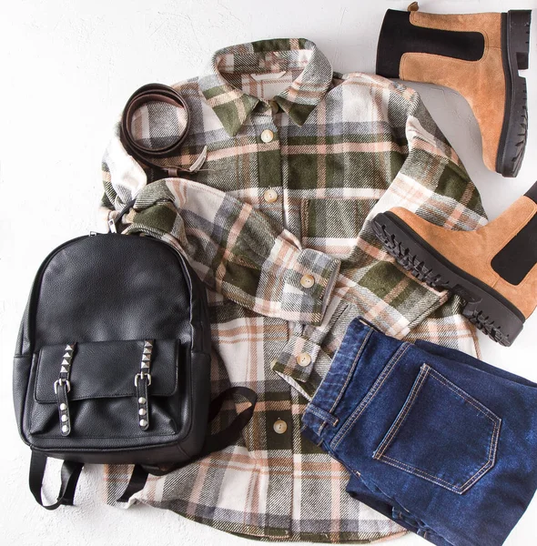 Set of clothes. Checked shirt, jeans, beige boots, leather backpack. Shoes and wardrobe. Womens modern style. Clothing top view. Woman clothes and accessories casual spring winter autumn outfit.