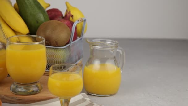 黄色令人神清气爽的夏季饮料 新鲜的芒果汁橙汁桌上的果篮 一杯果汁 厨房里新鲜的水果和果汁 维生素饮料 猕猴桃 — 图库视频影像