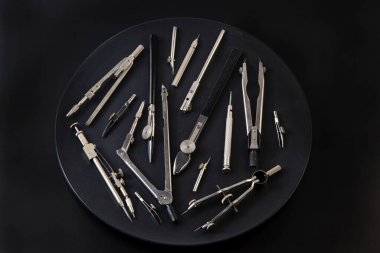 Compass for drawing. Set of old different compasses. Retro metal compasses and drafting tools on a black background. Drawing pen. Tool for study draw