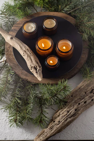 Soy candles burn in glass jars. Comfort at home. Candle in a brown jar. Scent and light. Scented handmade candle. Aroma therapy. Christmas tree and winter mood. Cozy decor. Festive decoration