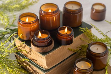 A set of different aroma candles in brown glass jars. Scented handmade candle. Soy candles are burning in a jar. Aromatherapy and relax in spa and home. Fire in brown jar. Yellow flowers