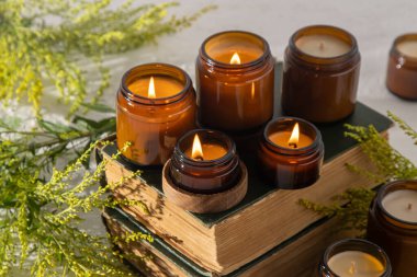 A set of different aroma candles in brown glass jars. Scented handmade candle. Soy candles are burning in a jar. Aromatherapy and relax in spa and home. Fire in brown jar. Yellow flowers