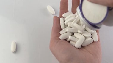Eline bir doz tablet dök. Tablet tedavisi. Vitaminler, beslenme takviyesi, ağrı kesiciler ve antipiretikler. Eczacılık. Eczane. Beyaz haplar. Sağlık tedavisi