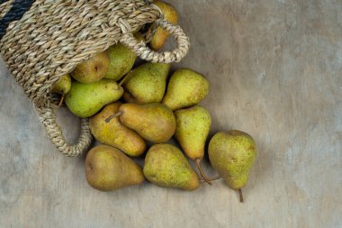 Ahşap bir arka planda sepetteki armutlar. Meyve hasadı. Sonbahar hala hayattır. Armut çeşitliliğinde Bera Konferansı. Vitamin yiyeceği..